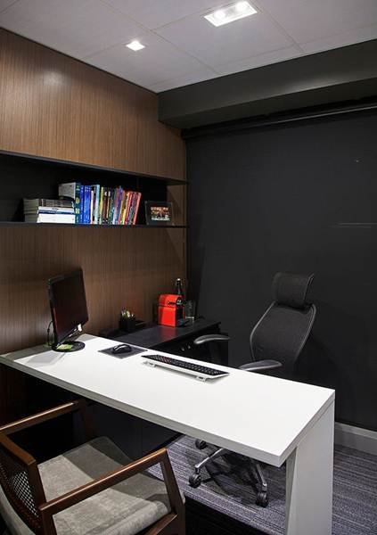 A small office with a white countertop contrasting against a black wall, designed to face clients.